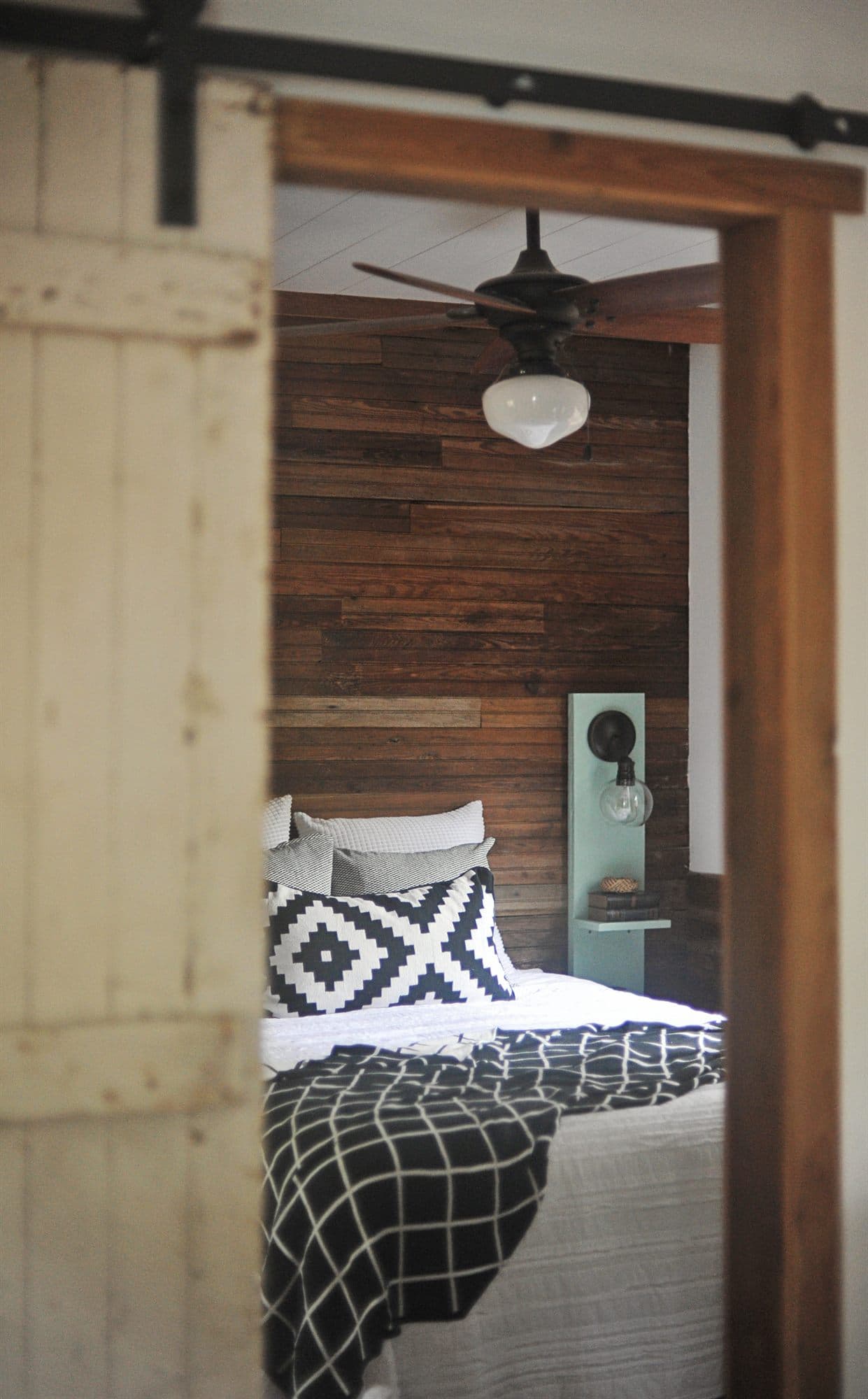 The bed seen through a sliding barn door on a black rail