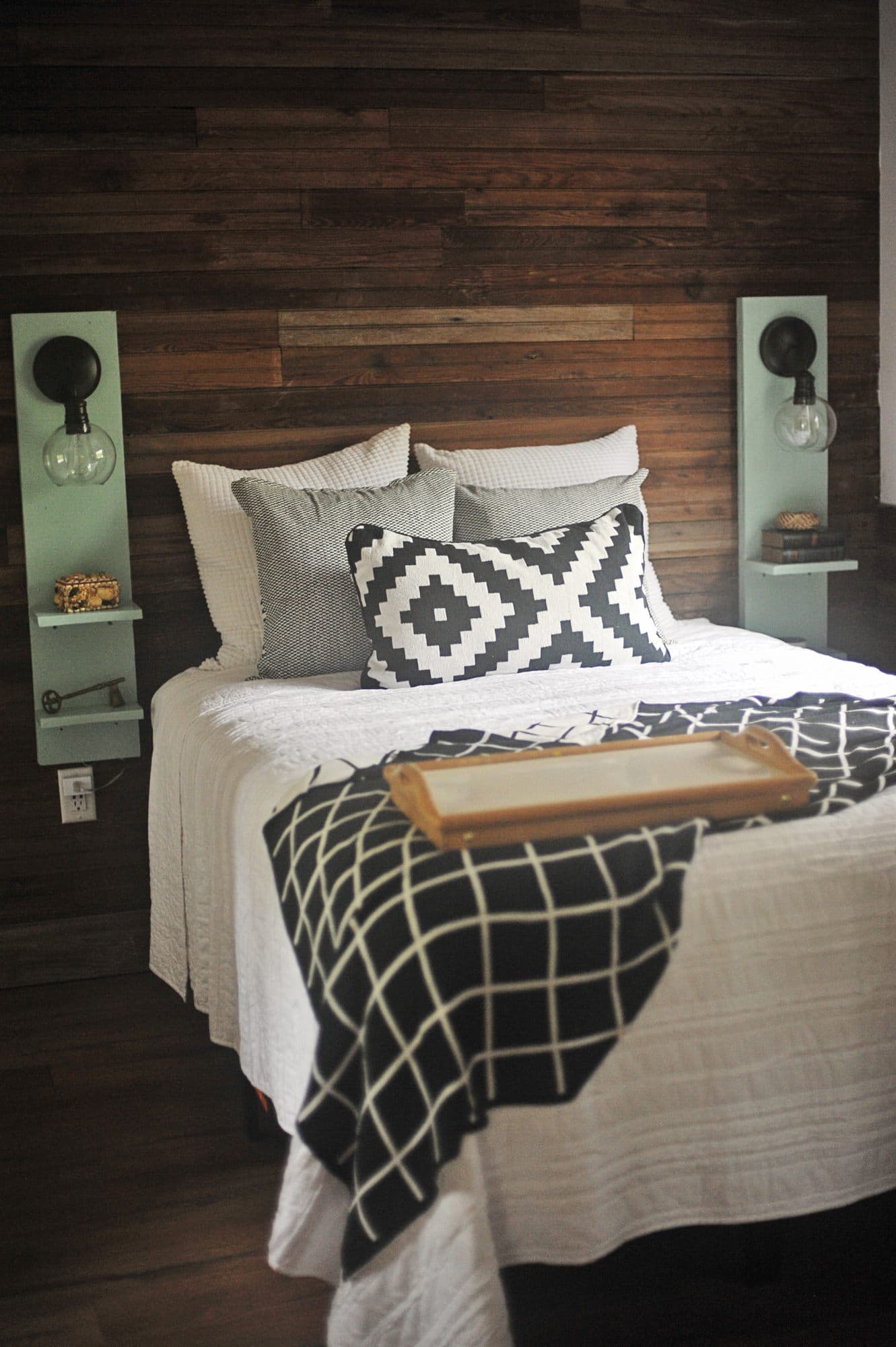 The bed made up in white against a wall of reclaimed timber boards